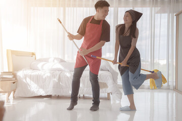 A beautiful young loving couple is smiling while doing a clean The bedroom at home. © PAPALAH
