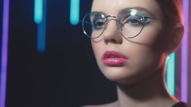 Fashion model portrait. Eyewear design. Woman in round eyeglasses posing in blue neon lights.