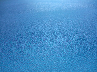 Dew drops on the roof of the blue car In the morning as a background
