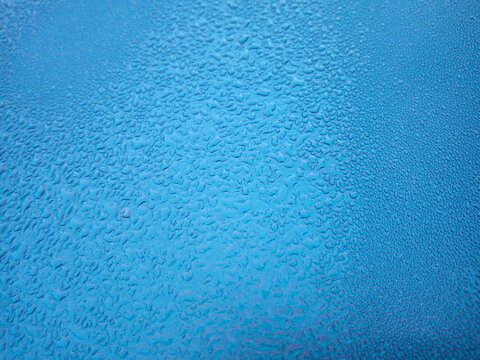 Dew drops on the roof of the blue car In the morning as a background