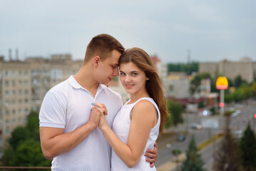 young man and woman hold hands on the roof in the evening