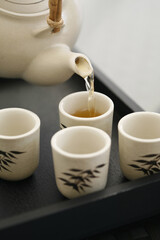 Pouring tea into teacups on tray