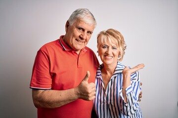 Senior beautiful couple standing together over isolated white background Showing palm hand and doing ok gesture with thumbs up, smiling happy and cheerful