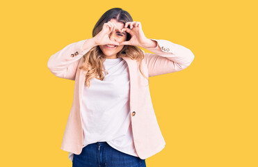 Young caucasian woman wearing business clothes doing heart shape with hand and fingers smiling looking through sign