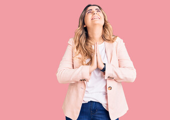 Young caucasian woman wearing business clothes begging and praying with hands together with hope expression on face very emotional and worried. begging.