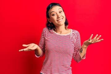 Young woman wearing casual clothes clueless and confused expression with arms and hands raised....