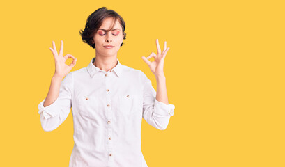 Beautiful young woman with short hair wearing elegant white shirt relax and smiling with eyes closed doing meditation gesture with fingers. yoga concept.