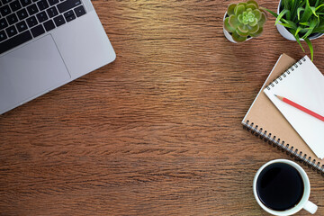 Wooden vintage office desk table with keyboard, notebook and coffee cup with equipment other office supplies. Business and finance concept.