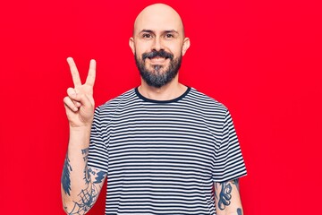 Fototapeta premium Young handsome man wearing casual clothes smiling with happy face winking at the camera doing victory sign. number two.