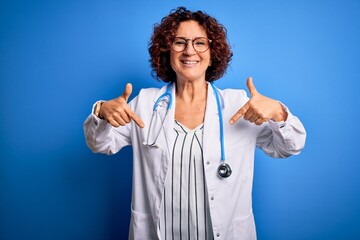 Middle age curly hair doctor woman wearing coat and stethoscope over blue background looking...
