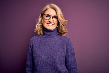Middle age beautiful blonde woman wearing casual purple turtleneck sweater and glasses with a happy...