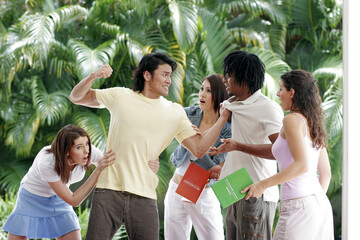 A guy trying to beat up an African American guy while their girlfriends holding them back