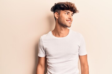 Young hispanic man wearing casual clothes looking to side, relax profile pose with natural face and...