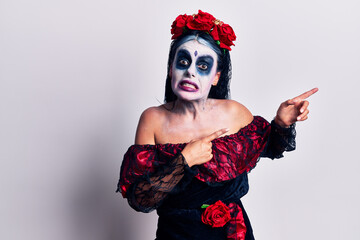 Young woman wearing mexican day of the dead makeup pointing aside worried and nervous with both hands, concerned and surprised expression