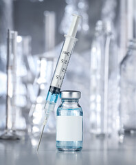 Healthcare and pharmaceutical drugs concept with syringe and vaccine vial with blue liquid. Drug vial has blank white label copyspace.