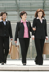 Three ladies in formal wear walking together carrying paper bags