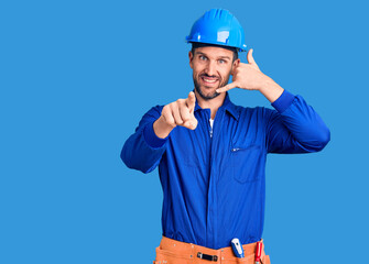 Young handsome man wearing worker uniform and hardhat smiling doing talking on the telephone...