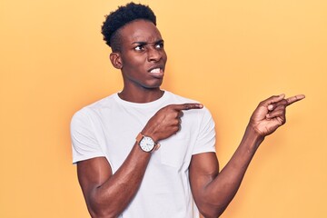 Young african american man wearing casual clothes pointing aside worried and nervous with both...