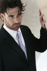 A guy in black suit and purple tie standing near the wall