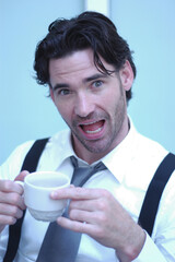 A man holding a cup of coffee with his eyes and mouth wide opened
