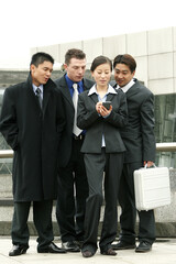 Fototapeta premium Three guys in business suits watching as a lady tapping on her palmtop