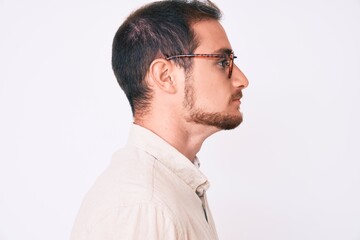 Obraz premium Young handsome man wearing casual clothes and glasses looking to side, relax profile pose with natural face with confident smile.