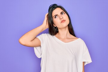 Obraz na płótnie Canvas Young beautiful brunette woman wearing casual white t-shirt over purple background confuse and wondering about question. Uncertain with doubt, thinking with hand on head. Pensive concept.
