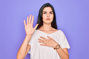 Young beautiful brunette woman wearing casual white t-shirt over purple background Swearing with...