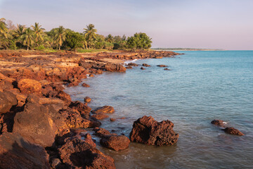 Unspoiled beach at sunset. Rocky landscape, green trees and palm trees. Coastline of Timor sea. Dundee Beach. Northern Territory NT, Australia