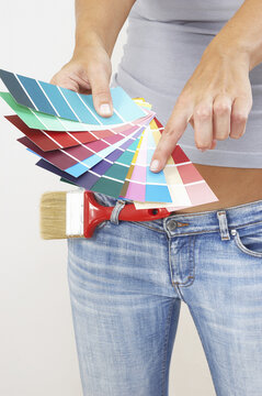 A woman in jeans pointing at the selected colour from the colour cards