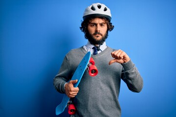 Handsome skater man with beard wearing security helmet holding skate over blue background with...