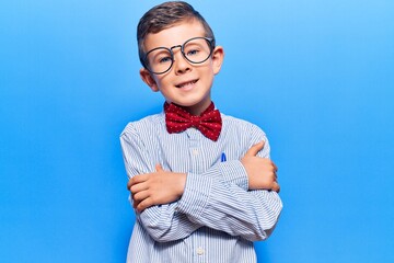 Cute blond kid wearing nerd bow tie and glasses happy face smiling with crossed arms looking at the...