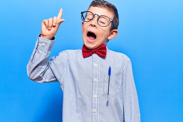 Naklejka premium Cute blond kid wearing nerd bow tie and glasses pointing finger up with successful idea. exited and happy. number one.