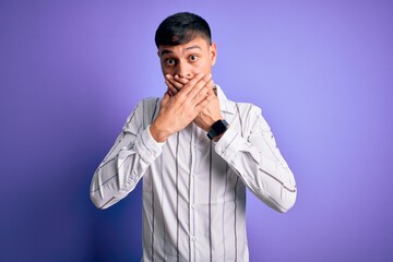 Young handsome hispanic man wearing elegant business shirt standing over purple background shocked covering mouth with hands for mistake. Secret concept.