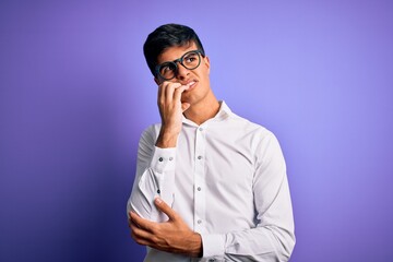 Young handsome business man wearing shirt and glasses over isolated purple background looking stressed and nervous with hands on mouth biting nails. Anxiety problem.
