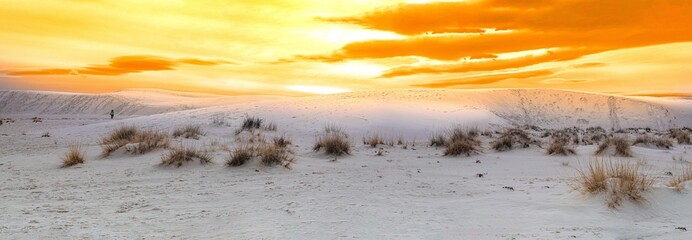 Golden sunset over white sands national park, with gypsum sand. Figure walking on dunes for scale. 