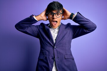 Young handsome business man wearing jacket and glasses over isolated purple background Crazy and scared with hands on head, afraid and surprised of shock with open mouth