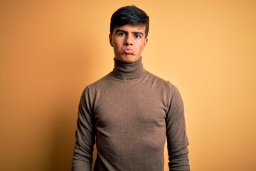 Fototapeta premium Young handsome man wearing casual turtleneck sweater over isolated yellow background depressed and worry for distress, crying angry and afraid. Sad expression.