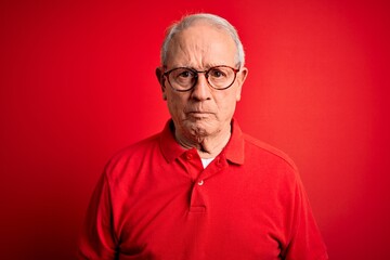 Grey haired senior man wearing glasses and casual t-shirt over red background skeptic and nervous, frowning upset because of problem. Negative person.