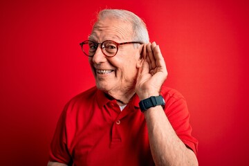 Grey haired senior man wearing glasses and casual t-shirt over red background smiling with hand...