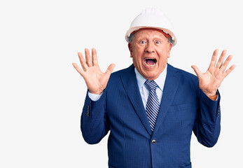 Senior handsome grey-haired man wearing suit and architect hardhat celebrating surprised and amazed for success with arms raised and open eyes. winner concept.