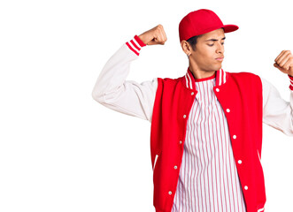 Young african amercian man wearing baseball uniform showing arms muscles smiling proud. fitness concept.