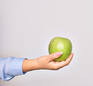 Hand of caucasian young woman holding green apple fruit over isolated white background