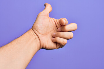 Hand of caucasian young man showing fingers over isolated purple background pointing forefinger to the camera, choosing and indicating towards direction