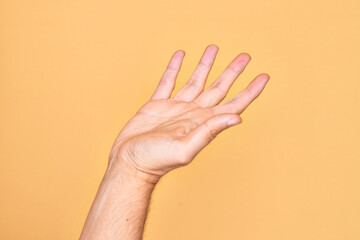 Hand of caucasian young man showing fingers over isolated yellow background presenting with open palm, reaching for support and help, assistance gesture