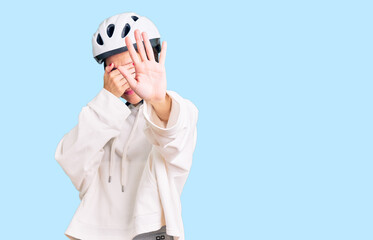 Beautiful brunette young woman wearing bike helmet and sporty clothes covering eyes with hands and doing stop gesture with sad and fear expression. embarrassed and negative concept.