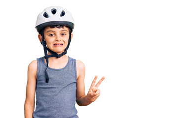 Little cute boy kid wearing bike helmet smiling with happy face winking at the camera doing victory sign. number two.