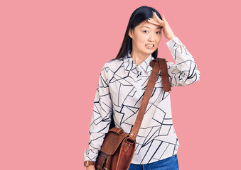 Fototapeta premium Young beautiful chinese woman holding briefcase stressed and frustrated with hand on head, surprised and angry face
