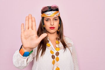 Young hispanic hippie woman wearing fashion boho style and sunglasses over pink background doing...