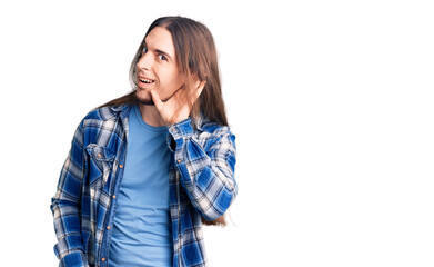 Fototapeta premium Young adult man with long hair wearing casual shirt smiling with hand over ear listening an hearing to rumor or gossip. deafness concept.